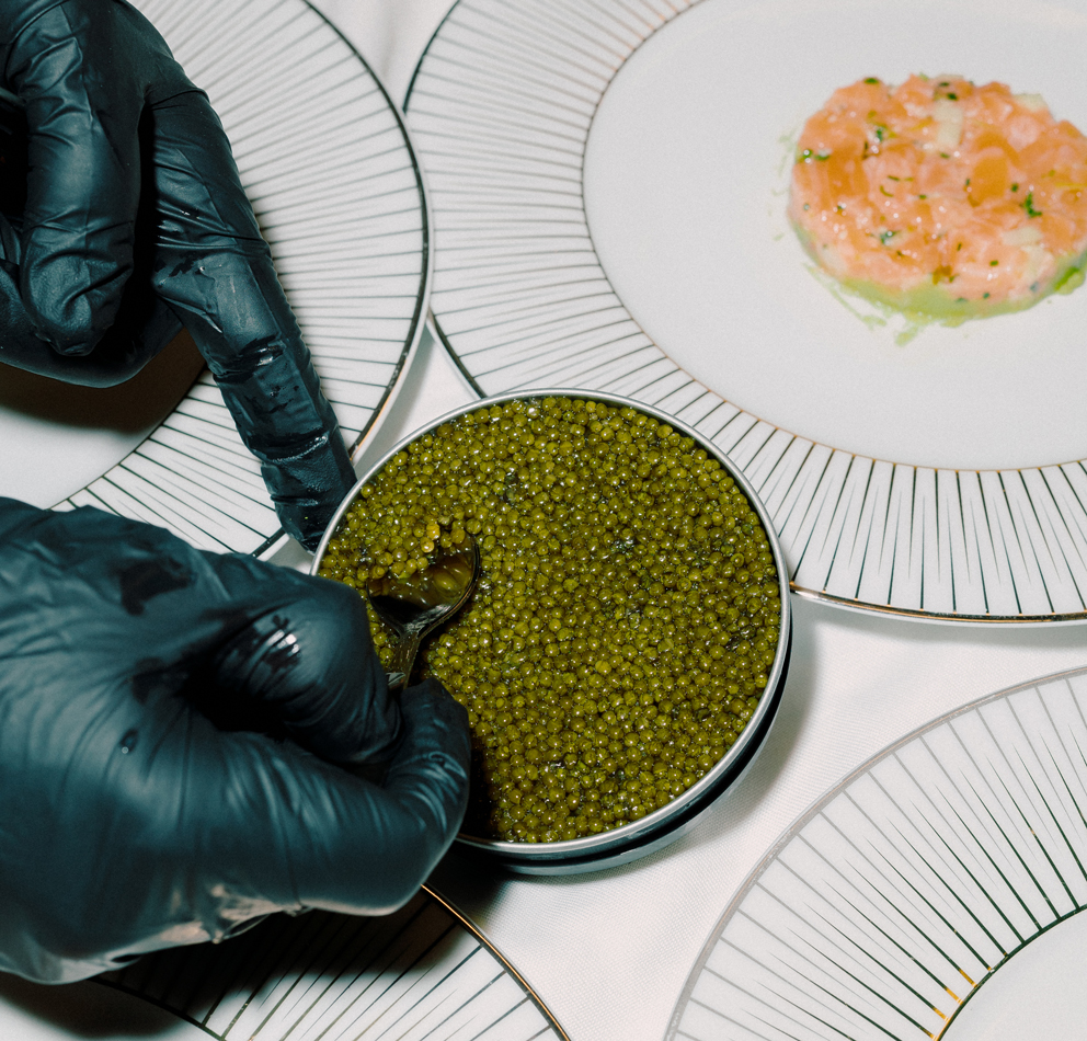 Fine Living Services – Caviar being spooned onto a plate by a person with black gloves