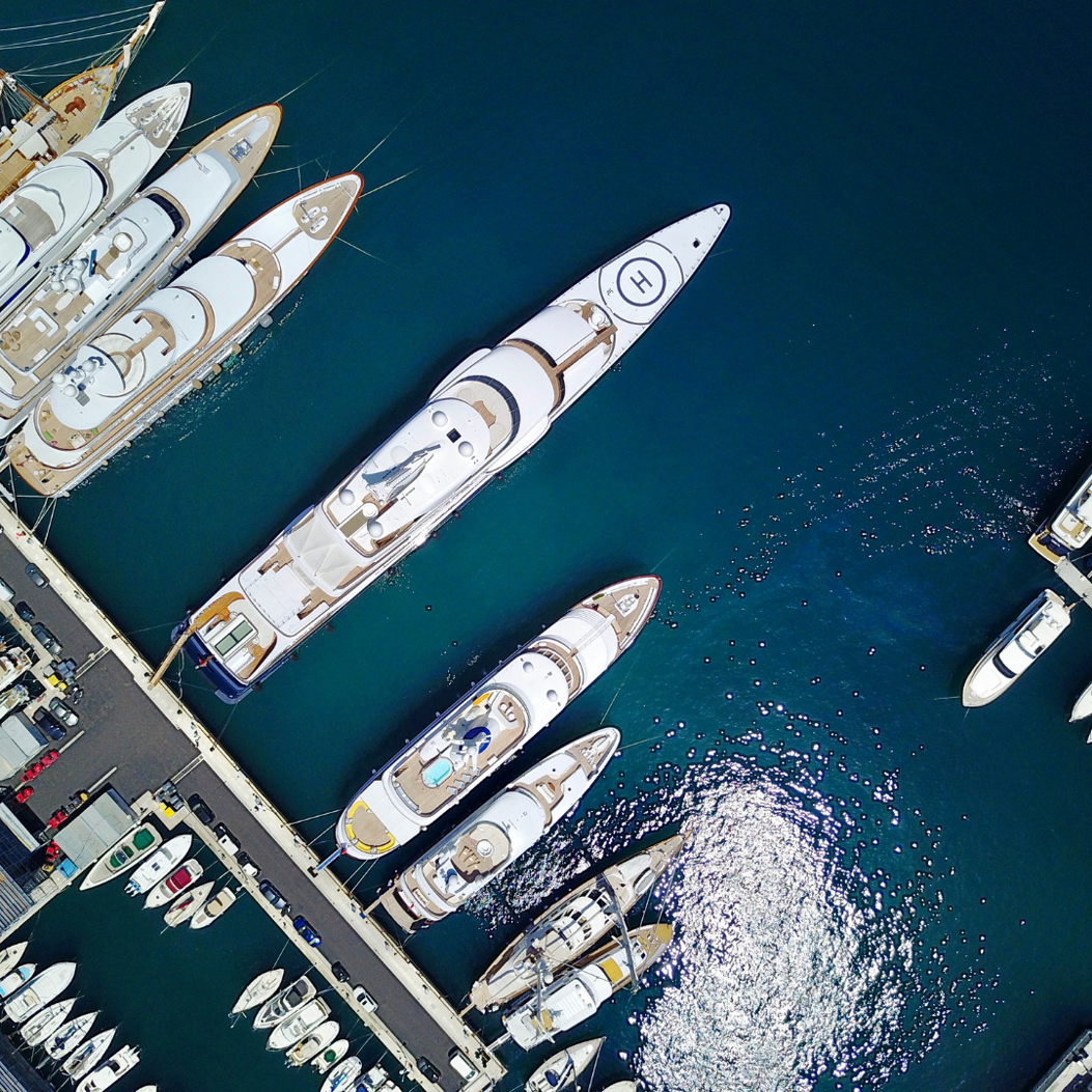 Fine Living Services – A drone shot of several large superyachts docked in a marina