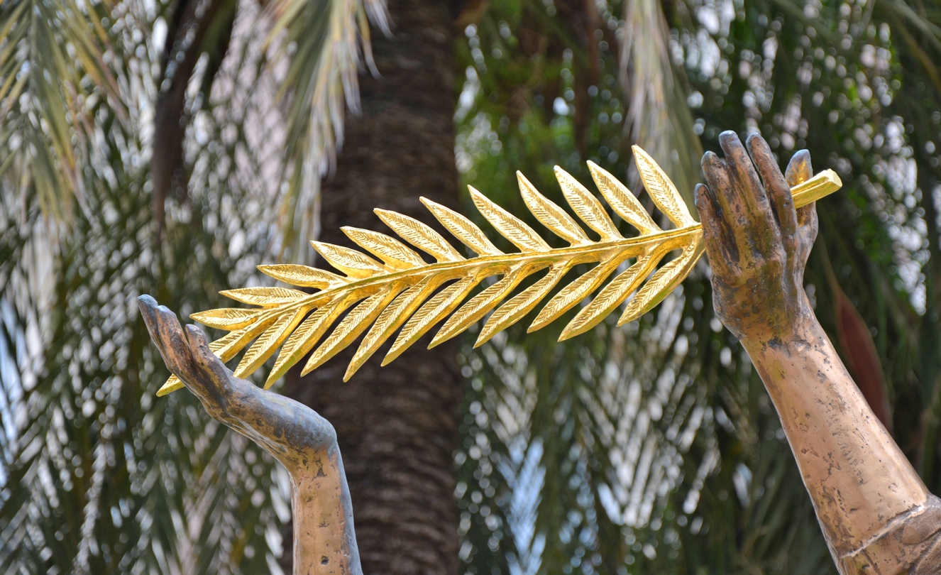Cannes Film Festival – a gold statue holding the Cannes Film Festival Palm D’Or Leaf.
